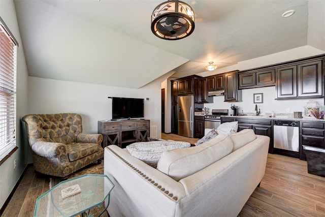 living room featuring sink, lofted ceiling, and light wood-type flooring