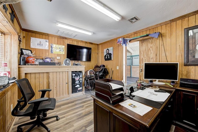 office area with wooden walls and light hardwood / wood-style floors