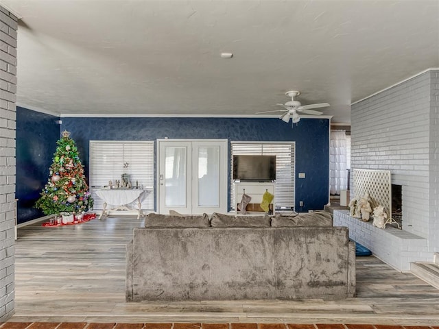 living room featuring ceiling fan, a fireplace, and wood-type flooring