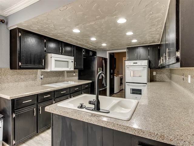 kitchen featuring a textured ceiling, decorative backsplash, white appliances, and sink