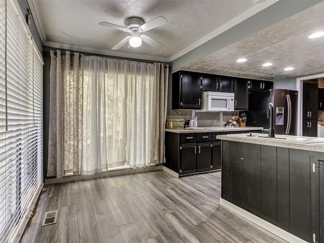 kitchen featuring stainless steel fridge, light wood-type flooring, a textured ceiling, and crown molding