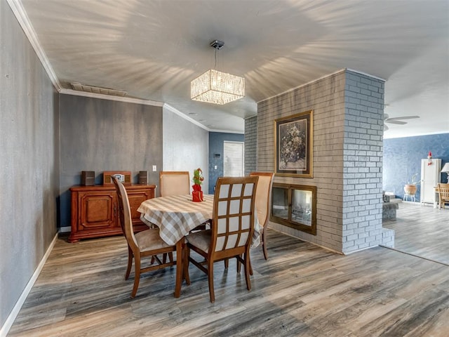 dining space with crown molding, hardwood / wood-style floors, and a notable chandelier