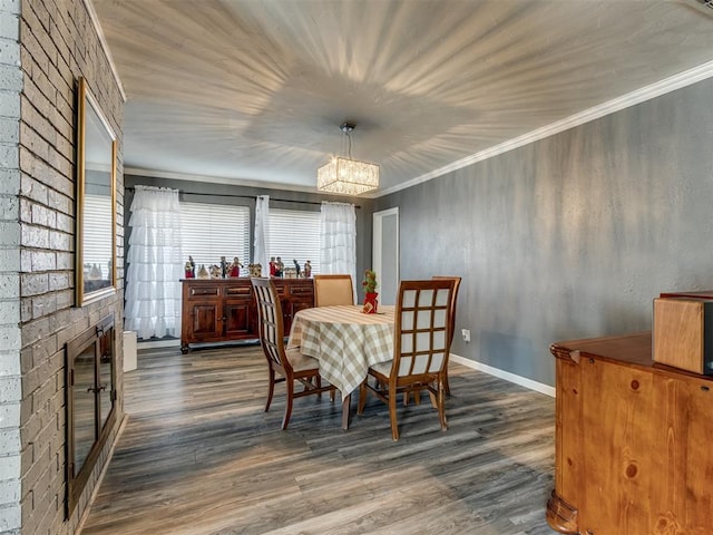 dining room with a chandelier, a fireplace, dark wood-type flooring, and ornamental molding