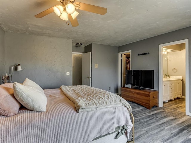 bedroom with ceiling fan, a spacious closet, hardwood / wood-style floors, connected bathroom, and a closet