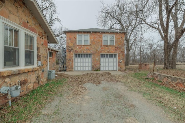 1315 S Division St, Guthrie, OK 73044 - view of side of home featuring stone siding, dirt driveway, and central air condition unit