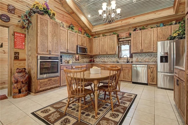 kitchen with appliances with stainless steel finishes, pendant lighting, light tile patterned floors, a notable chandelier, and lofted ceiling