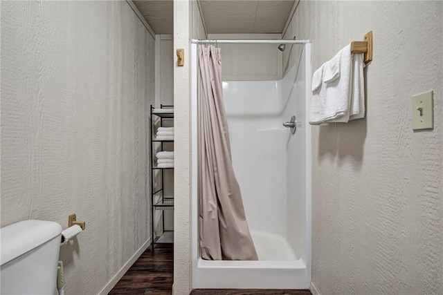 bathroom with a shower with shower curtain, hardwood / wood-style flooring, and toilet