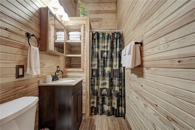 bathroom featuring wood-type flooring, vanity, toilet, and wooden walls