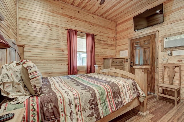 bedroom with wood-type flooring, an AC wall unit, wooden walls, ceiling fan, and wood ceiling