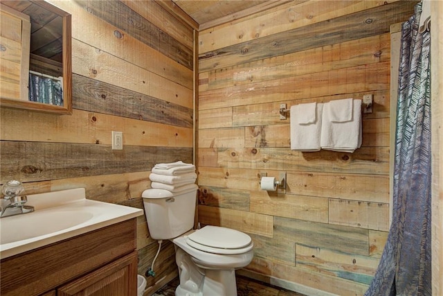 bathroom with vanity, toilet, and wooden walls