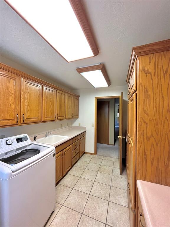 kitchen with light tile patterned floors, a textured ceiling, washer / clothes dryer, and sink