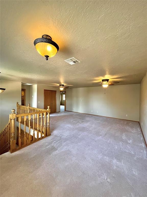 empty room with a textured ceiling, carpet floors, and ceiling fan