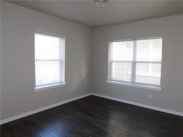 spare room with dark hardwood / wood-style floors and plenty of natural light