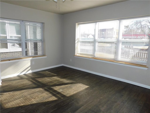 unfurnished room featuring plenty of natural light, dark wood-type flooring, and ceiling fan