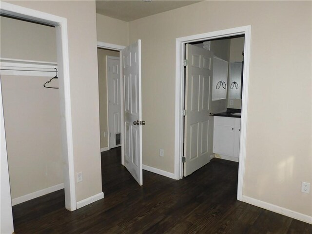 unfurnished bedroom with dark hardwood / wood-style flooring and ensuite bath