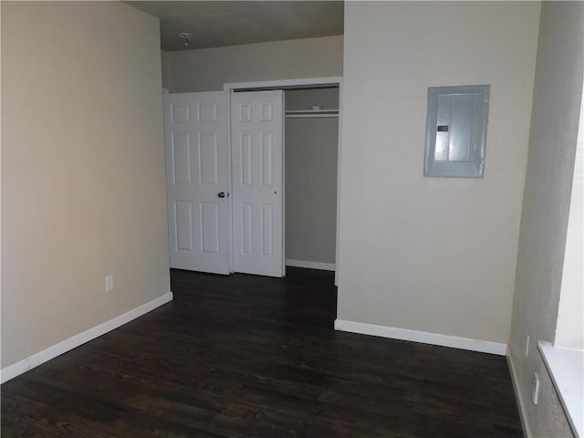 unfurnished bedroom featuring electric panel, a closet, and dark hardwood / wood-style flooring