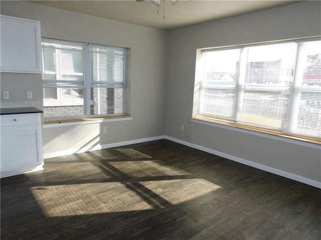 spare room with ceiling fan, dark wood-type flooring, and a wealth of natural light