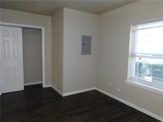 unfurnished bedroom featuring electric panel, dark hardwood / wood-style floors, and a closet