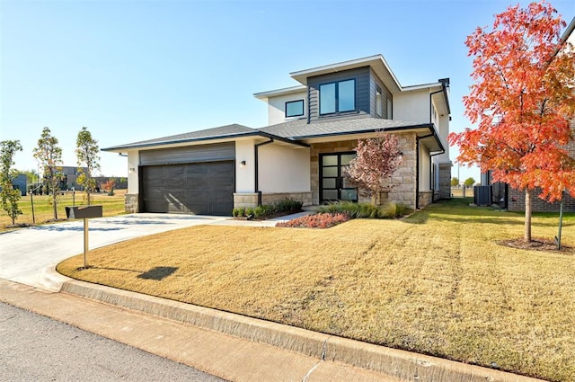 view of front of house with central air condition unit, a front yard, and a garage