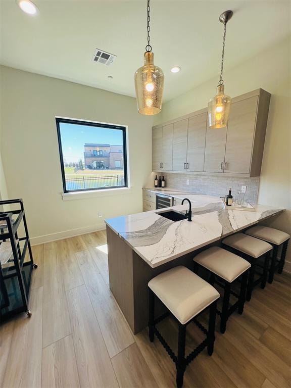 kitchen featuring backsplash, kitchen peninsula, light stone counters, and light hardwood / wood-style floors