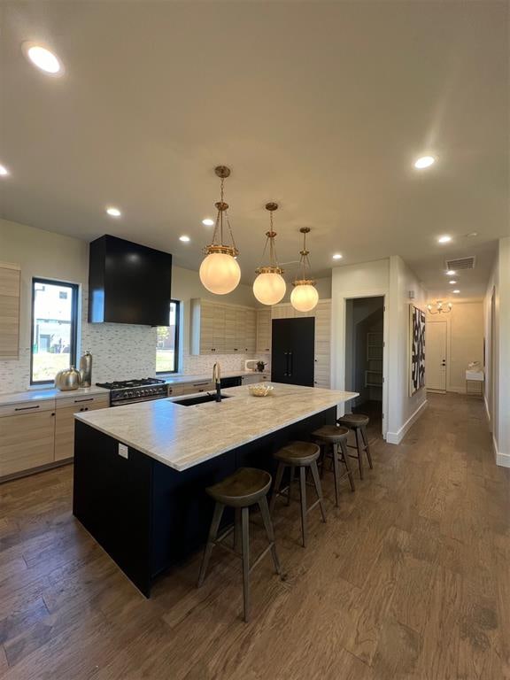 kitchen with dark hardwood / wood-style floors, hanging light fixtures, sink, and a large island with sink