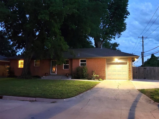 ranch-style house with an attached garage, fence, concrete driveway, a front yard, and brick siding