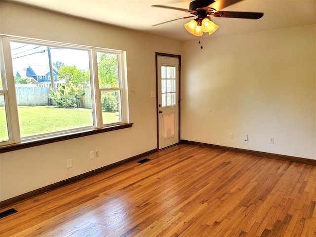 empty room with light wood finished floors, a ceiling fan, and visible vents