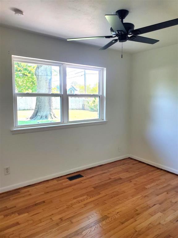 spare room with baseboards, ceiling fan, light wood-style floors, and visible vents