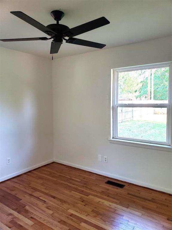 empty room featuring baseboards, ceiling fan, visible vents, and wood finished floors