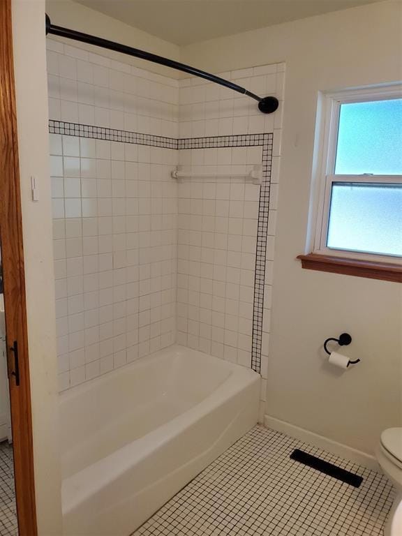 bathroom with toilet, washtub / shower combination, tile patterned flooring, and baseboards