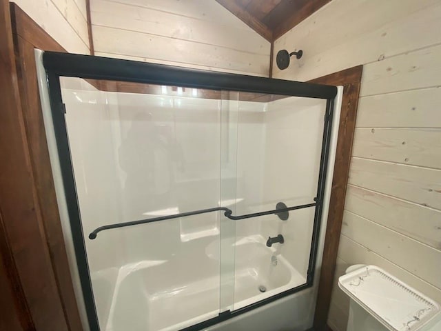 bathroom with shower / bath combination with glass door, wood walls, and vaulted ceiling