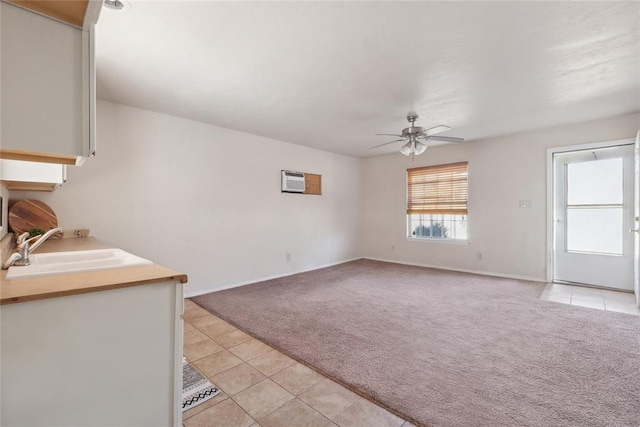 unfurnished living room featuring light carpet, an AC wall unit, ceiling fan, and sink