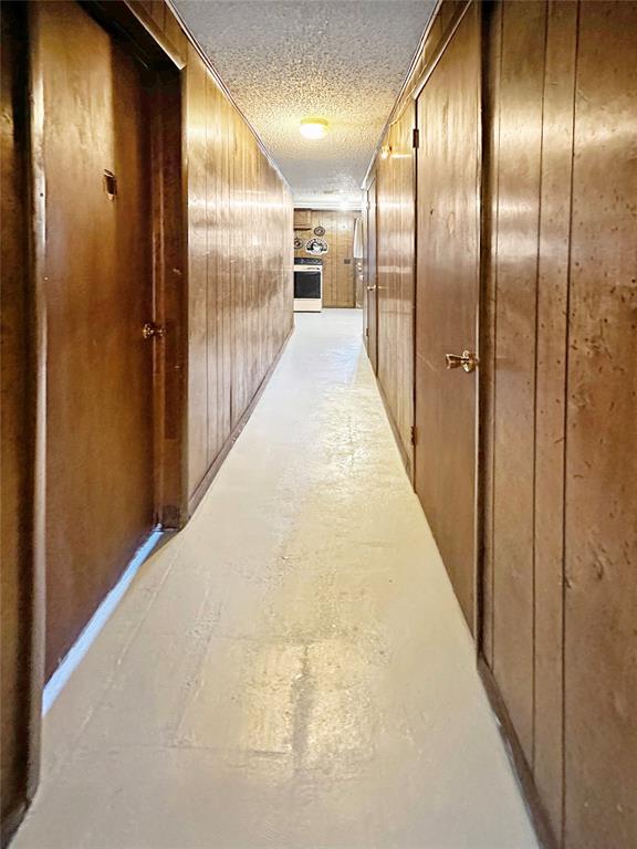 hallway with a textured ceiling and wooden walls