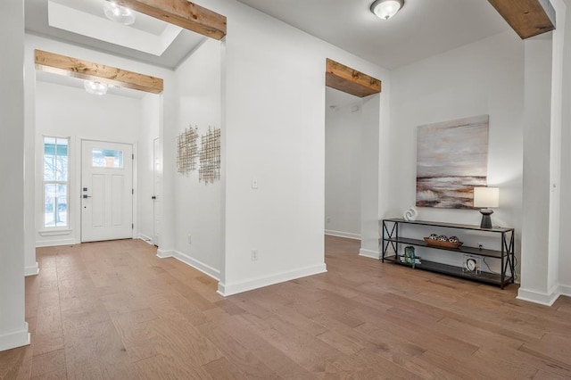 foyer with beamed ceiling and light wood-type flooring