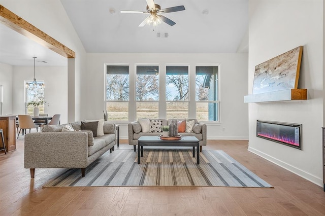 living room with hardwood / wood-style floors, vaulted ceiling, ceiling fan, and a healthy amount of sunlight