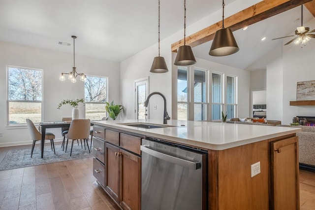 kitchen with stainless steel dishwasher, ceiling fan with notable chandelier, a kitchen island with sink, light hardwood / wood-style flooring, and hanging light fixtures