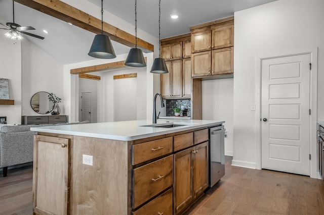 kitchen featuring sink, hanging light fixtures, stainless steel dishwasher, wood-type flooring, and a center island with sink