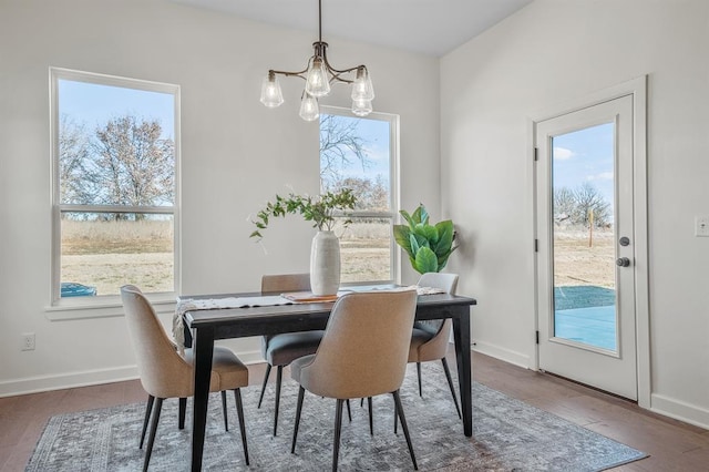 dining area featuring a notable chandelier, a healthy amount of sunlight, and dark hardwood / wood-style flooring