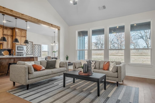 living room with high vaulted ceiling, a chandelier, and light wood-type flooring