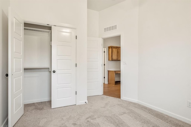 unfurnished bedroom featuring a closet and light colored carpet