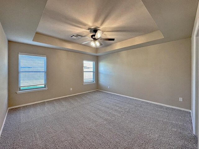 carpeted empty room featuring ceiling fan and a tray ceiling