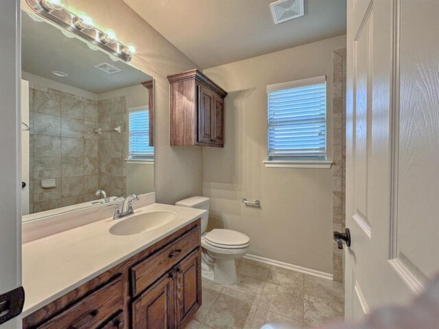 bathroom with tile patterned flooring, vanity, toilet, and a healthy amount of sunlight