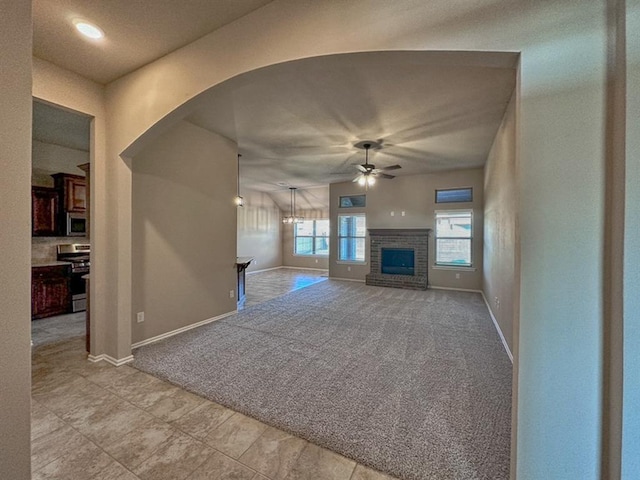 unfurnished living room with ceiling fan, a fireplace, and light colored carpet