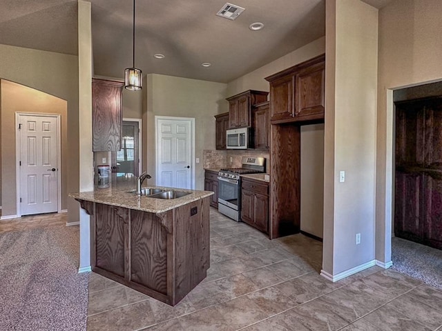 kitchen featuring sink, a kitchen breakfast bar, light stone counters, kitchen peninsula, and appliances with stainless steel finishes