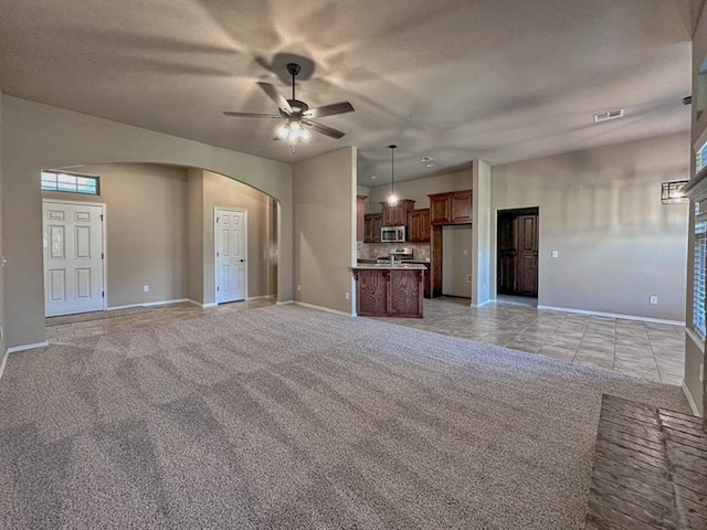 unfurnished living room featuring light colored carpet, plenty of natural light, and ceiling fan