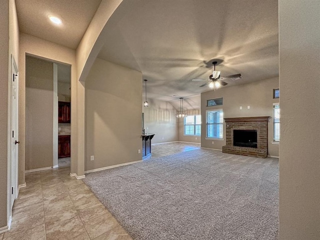 unfurnished living room with a textured ceiling, a fireplace, ceiling fan, and light carpet