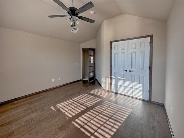 unfurnished bedroom with ceiling fan, a closet, dark wood-type flooring, and lofted ceiling