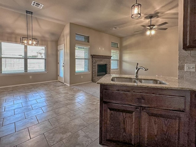 kitchen featuring light stone countertops, sink, and decorative light fixtures