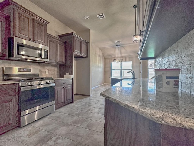 kitchen featuring sink, stainless steel appliances, light stone counters, lofted ceiling, and decorative light fixtures