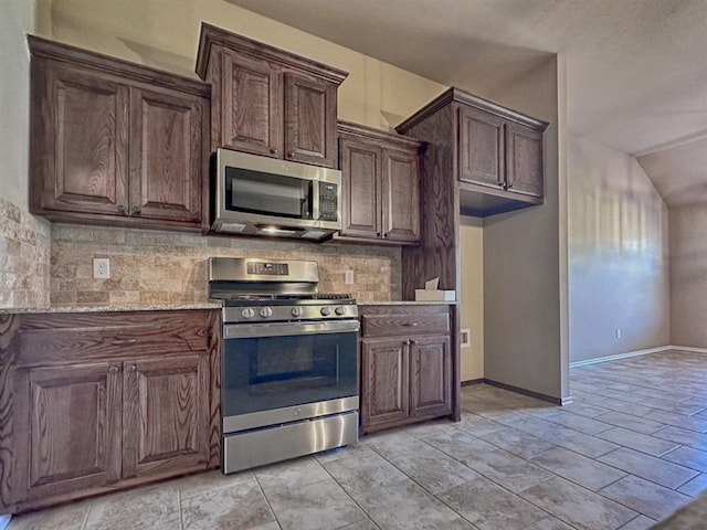 kitchen with dark brown cabinetry, lofted ceiling, stainless steel appliances, and tasteful backsplash